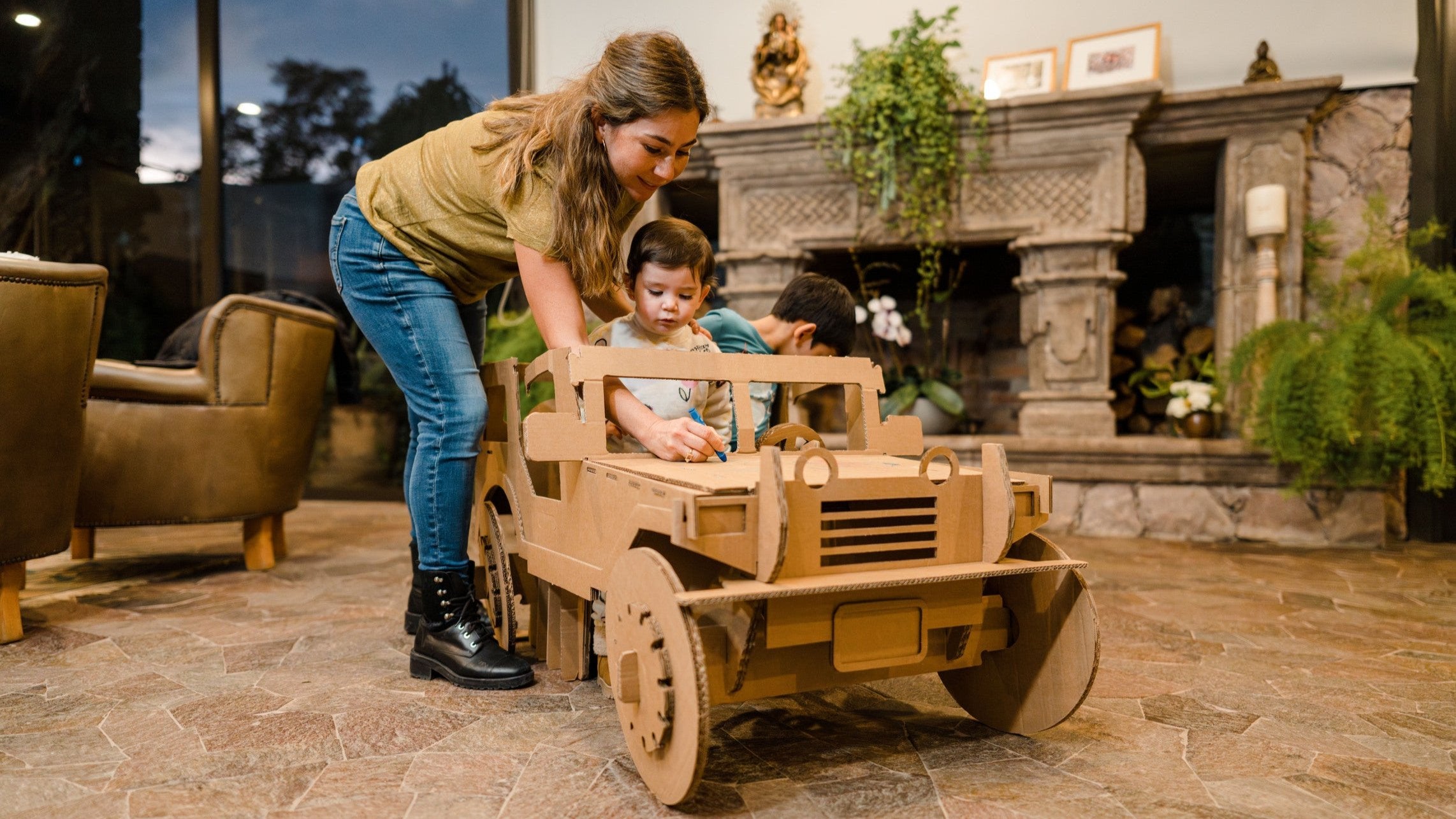 Mamá con sus dos hijos dibujando sobre un carrito de cartón.